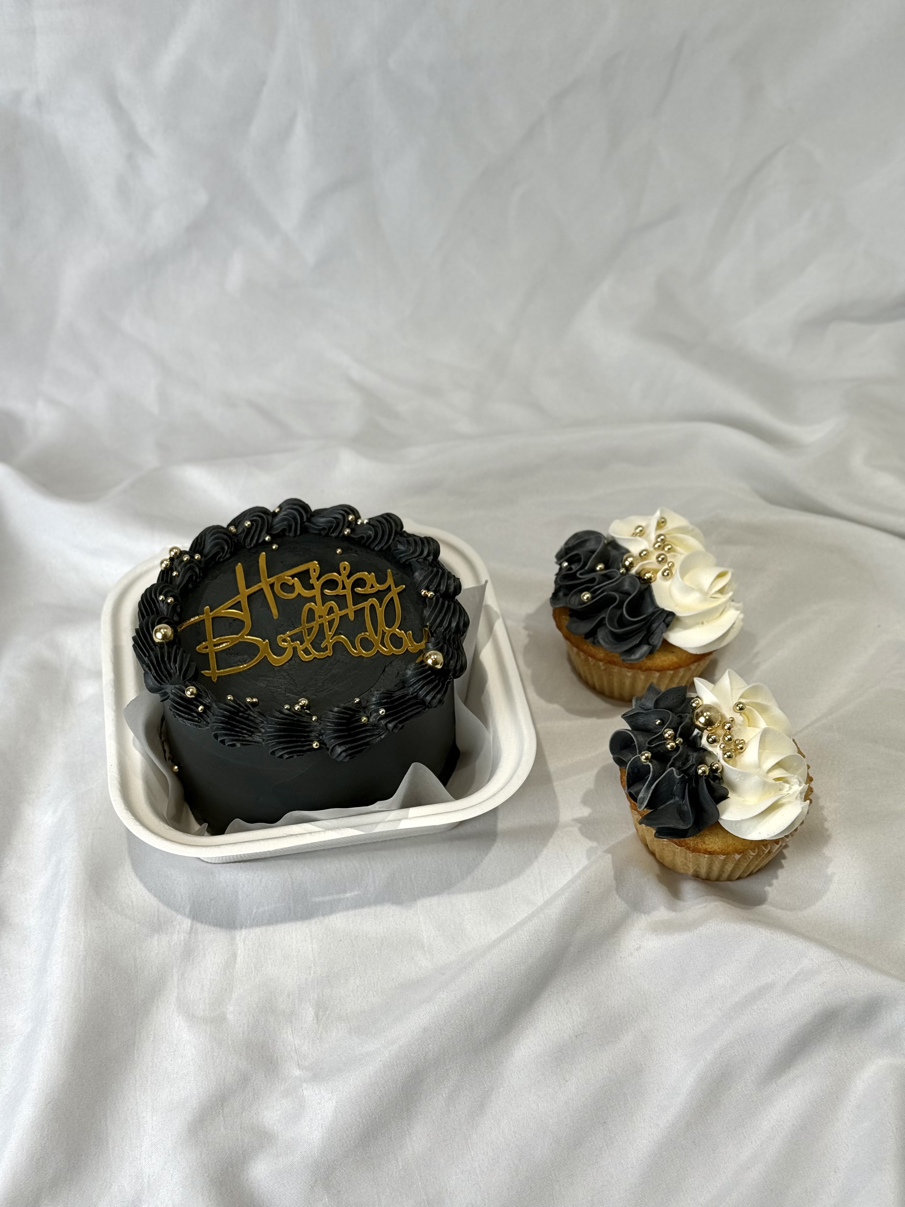 Black and gold birthday bento cake with matching cupcakes