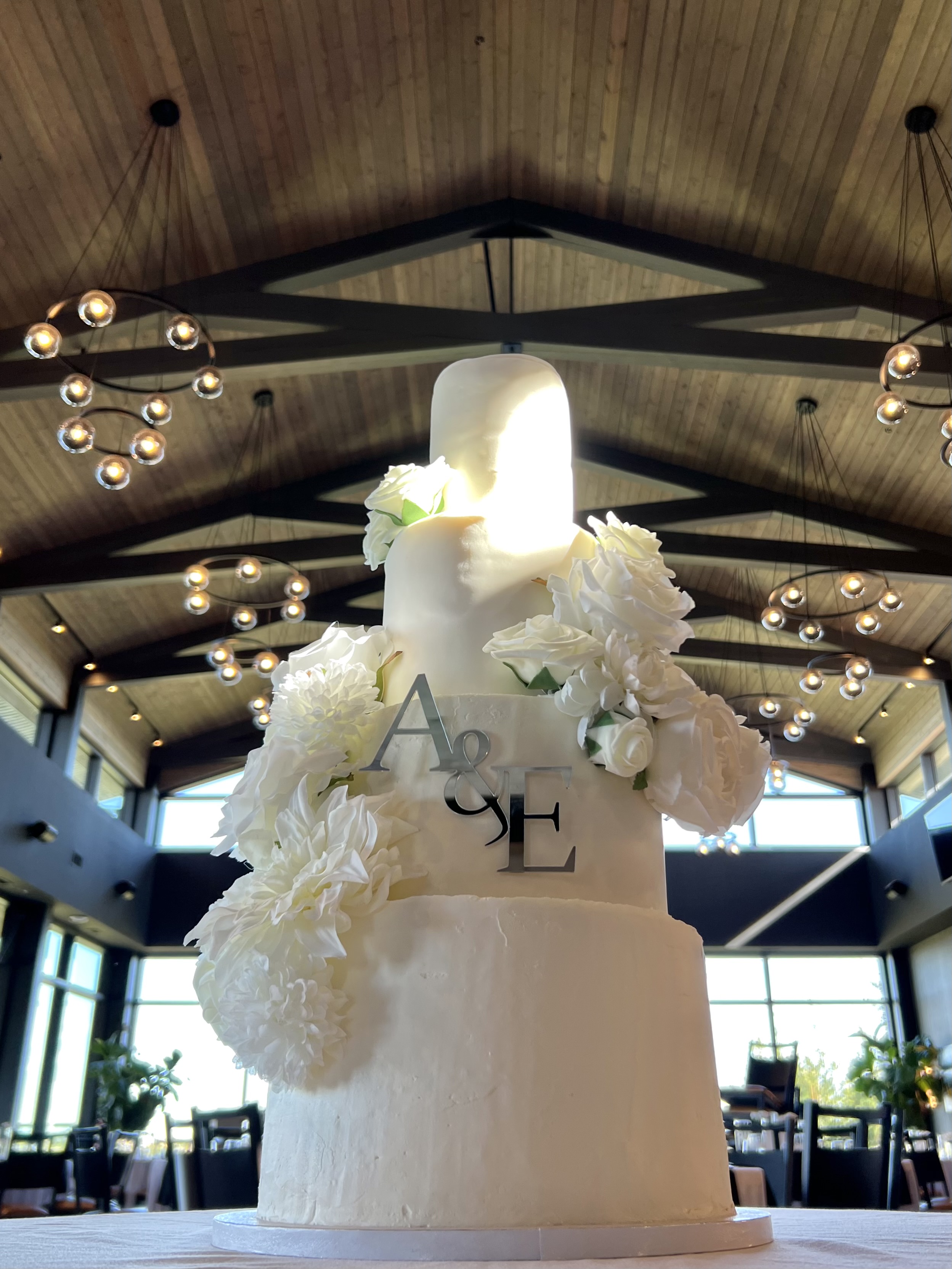 Grand four-tier white wedding cake with cascading roses in elegant reception venue