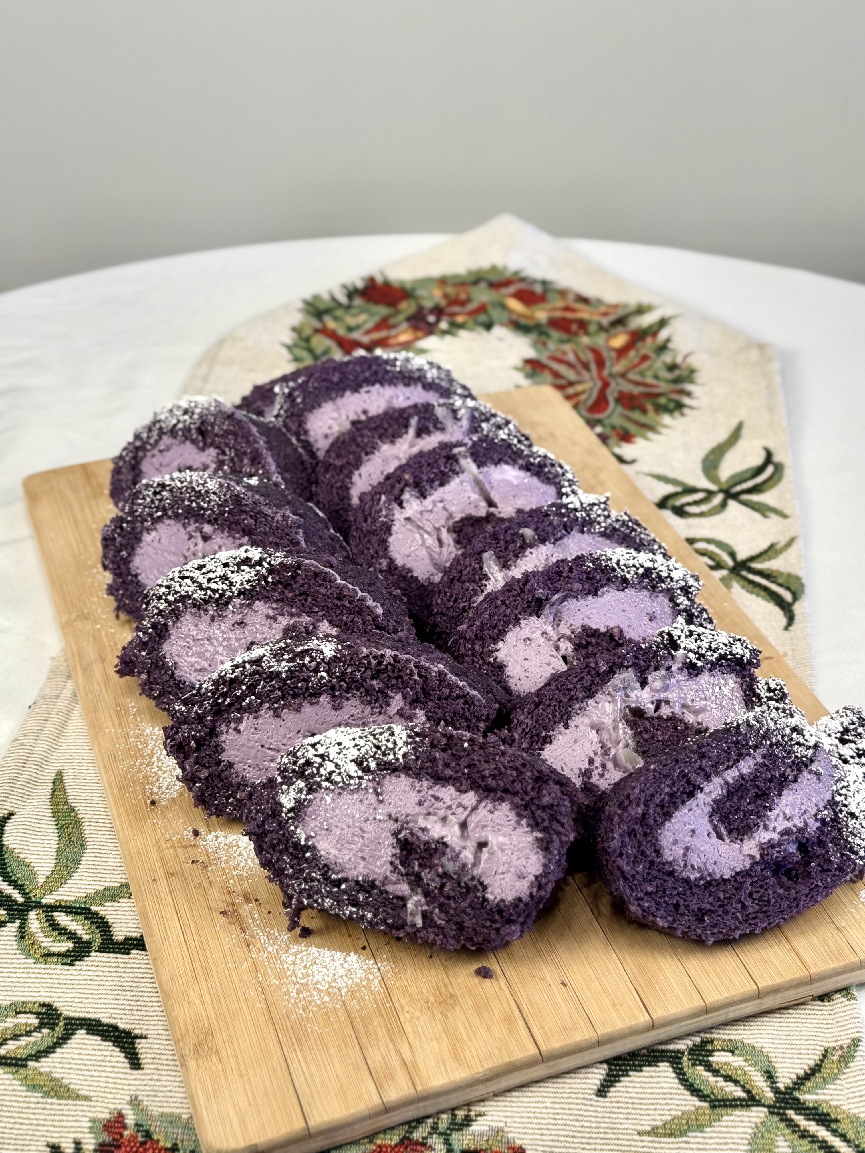 Purple ube Swiss roll cake sliced on a wooden board