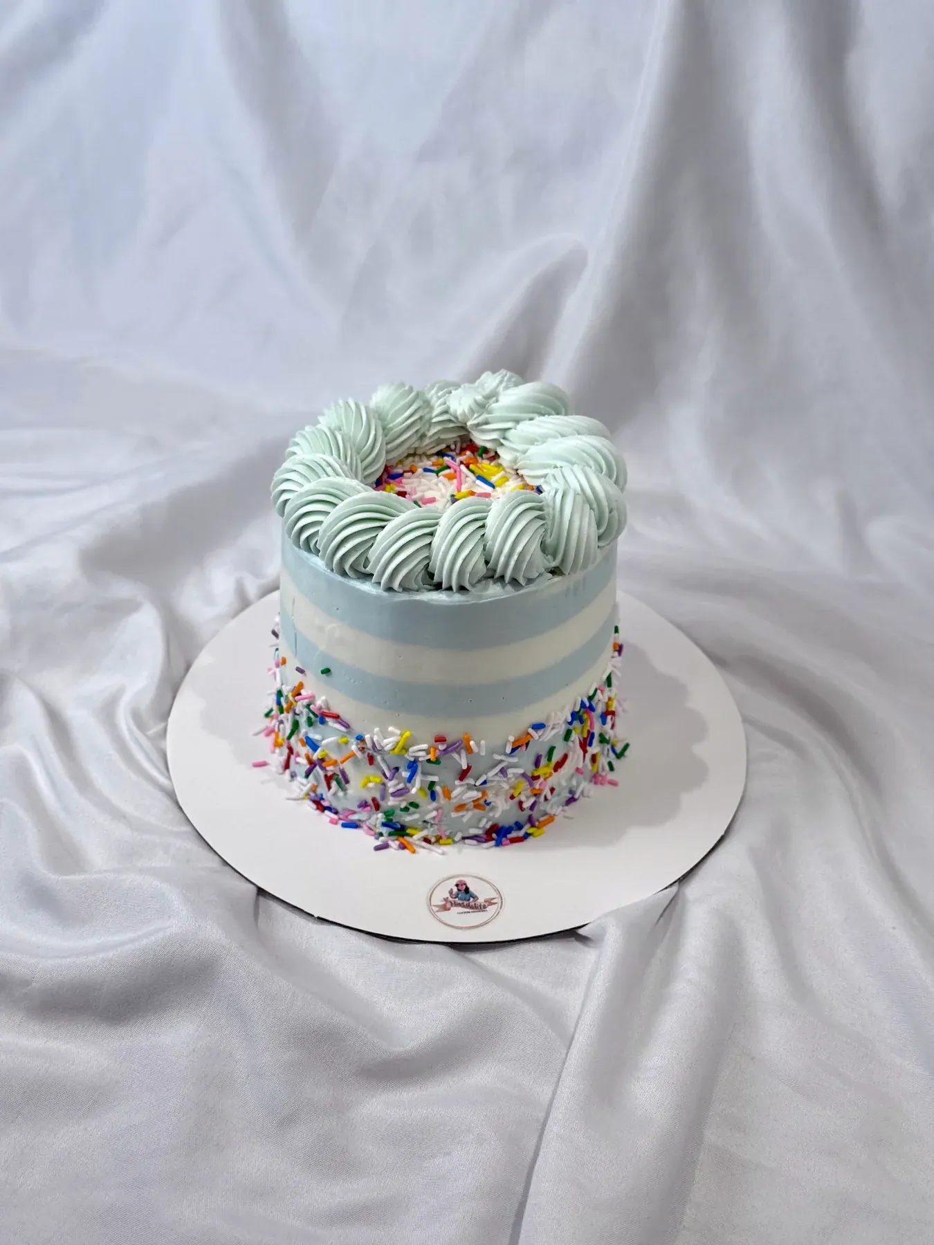 Small mint cake with piped rosettes and rainbow sprinkles