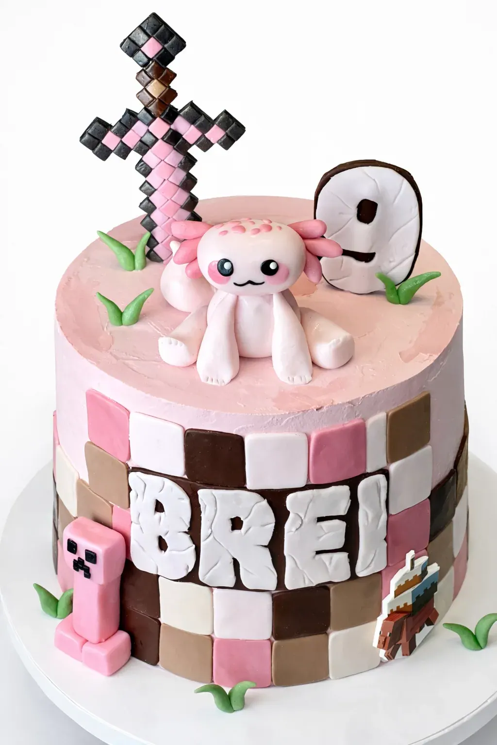 Pink and brown checkered Minecraft cake with a pink axolotl, a pixel sword and a number nine topper